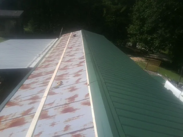 Old rusted panels beside newly installed green metal roofing — Wind Damage Roof Repair by Roofing Brothers in Pacific