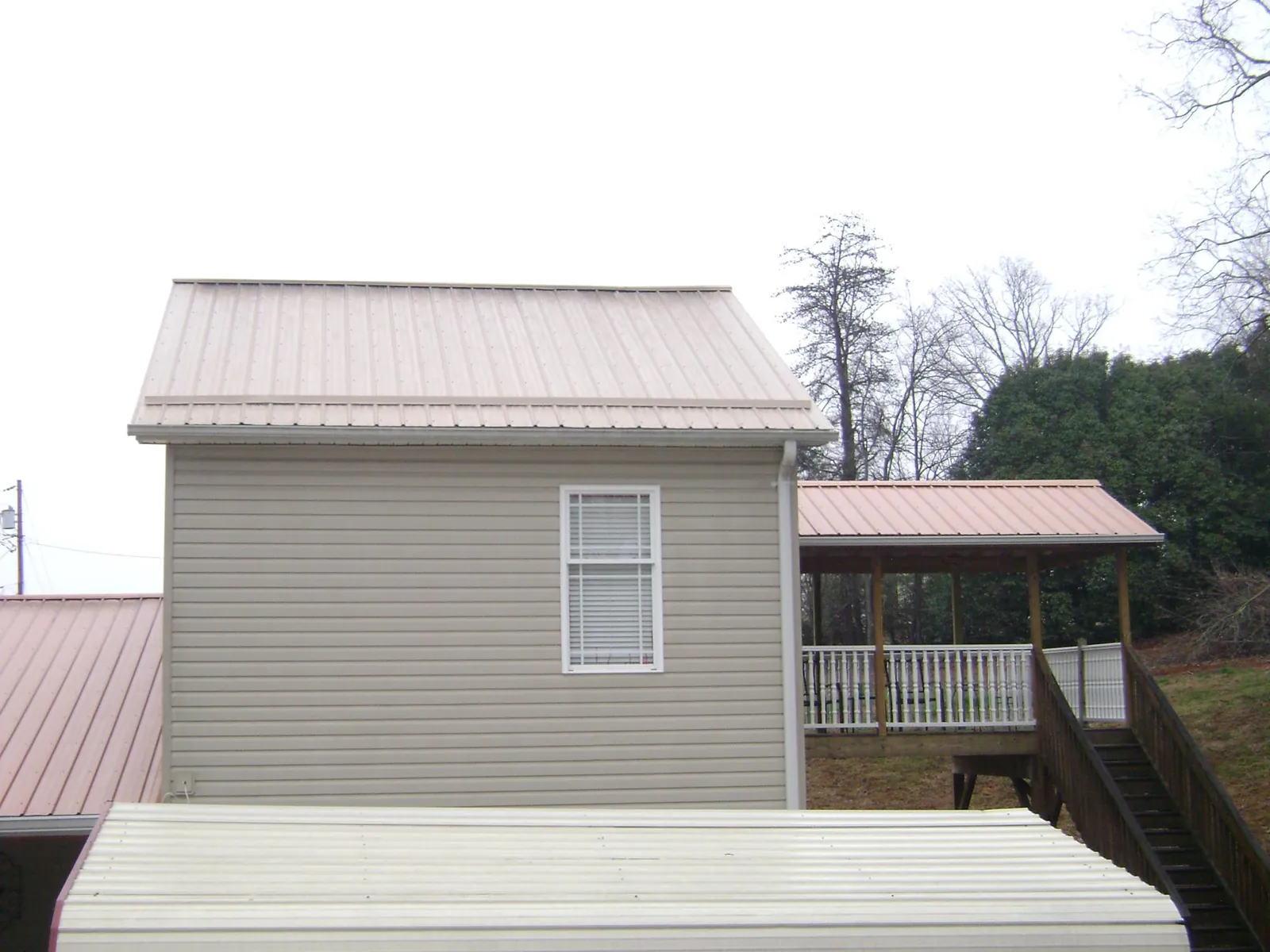 Tan metal roofs on a two story addition and attached porch, from a Roof Replacement job in Pacific
